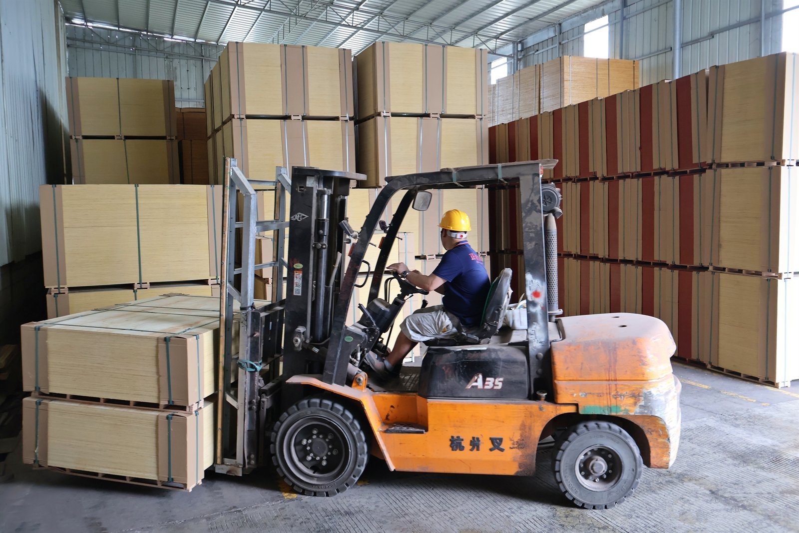 Forklift handling plywood pallets for export order preparation